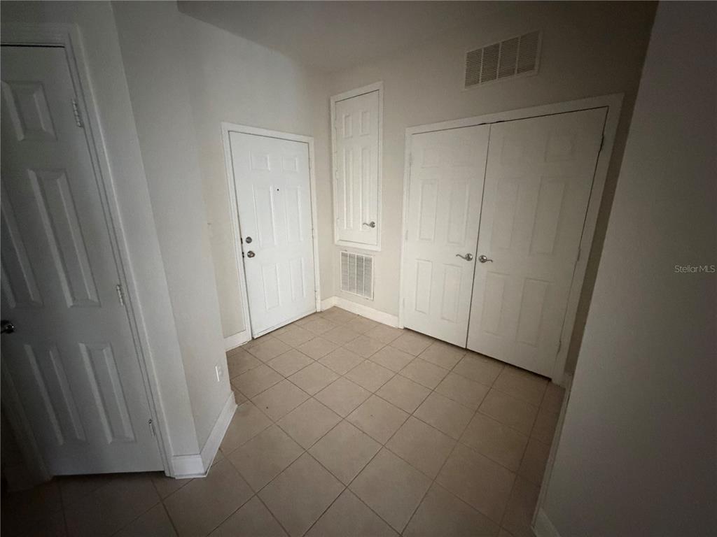 An entryway with tiled flooring, a white front door, and two sets of closet doors — 3326 ROBERT TRENT JONES DRIVE UNIT 10502, ORLANDO, FL