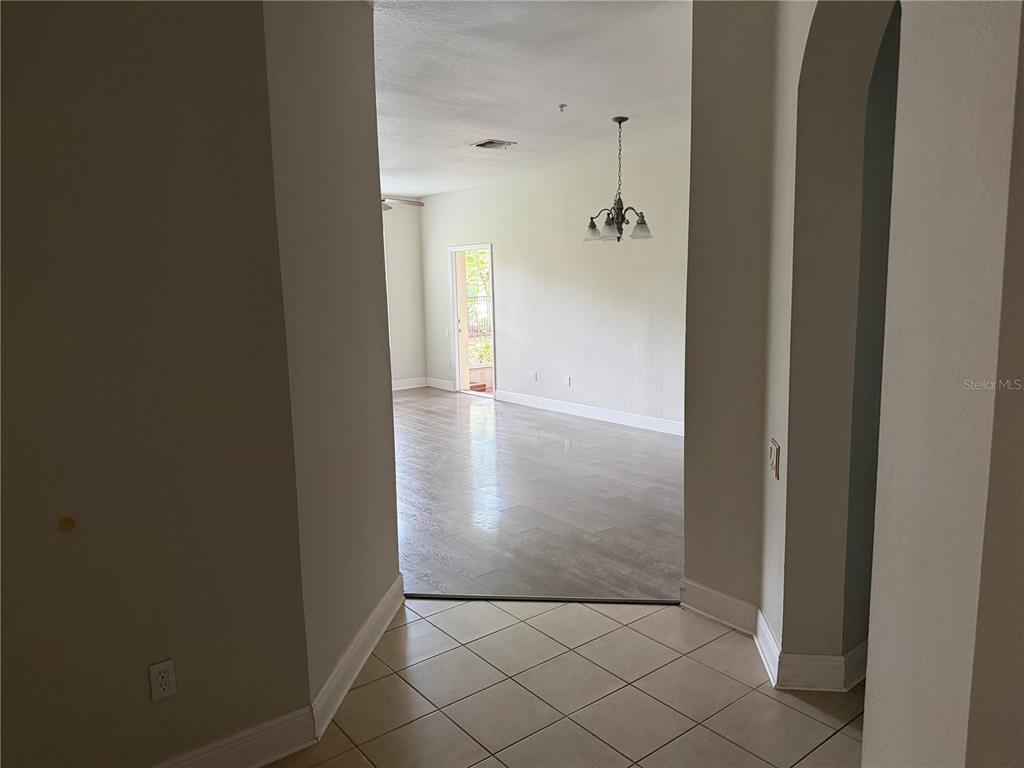 A tiled entryway leads into a living area with wood-look flooring and a chandelier — 3326 ROBERT TRENT JONES DRIVE UNIT 10502, ORLANDO, FL