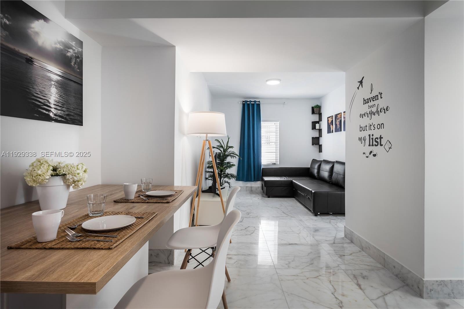 A dining area with a wooden table leads into a living room with marble floors — 807 Alton Rd, Miami Beach FL 33139, MIAMI BEACH, FL