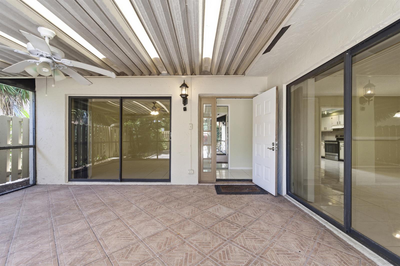 A covered patio features a tiled floor, a ceiling fan, and sliding glass doors — 729 NW 29th Avenue # D, Delray Beach FL 33445, DELRAY BEACH, FL