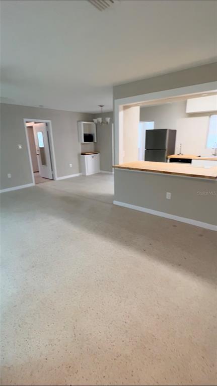 A view of a living area with beige carpet leading to a kitchen with a breakfast bar — 2618 LAKESHORE CIRCLE, PORT CHARLOTTE, FL