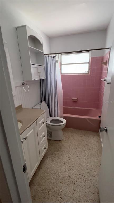A bathroom features a white vanity, a toilet, and a pink tiled bathtub with a shower — 2618 LAKESHORE CIRCLE, PORT CHARLOTTE, FL