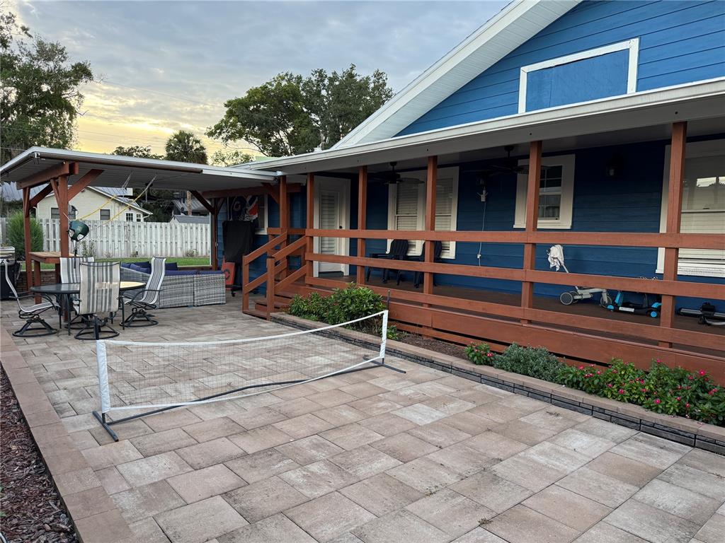 A blue house features a wooden porch, a paved patio, and a portable sports net — 1510 SANFORD AVE, SANFORD, FL