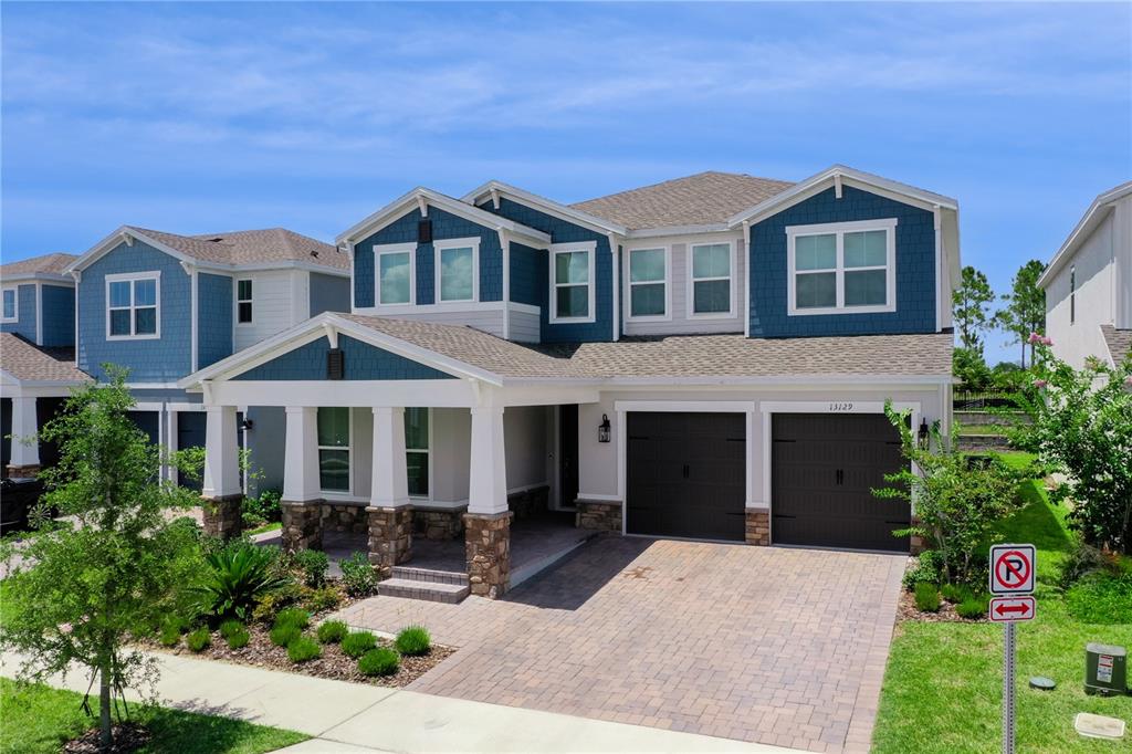 A two-story suburban house with blue siding, a stone-accented porch, and a two-car garage — 13129 FARO COURT, WINTER GARDEN, FL