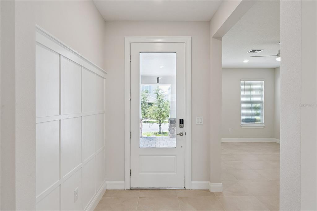 An entryway features a white door with a glass panel, board-and-batten wall trim, and tile flooring — 13129 FARO COURT, WINTER GARDEN, FL