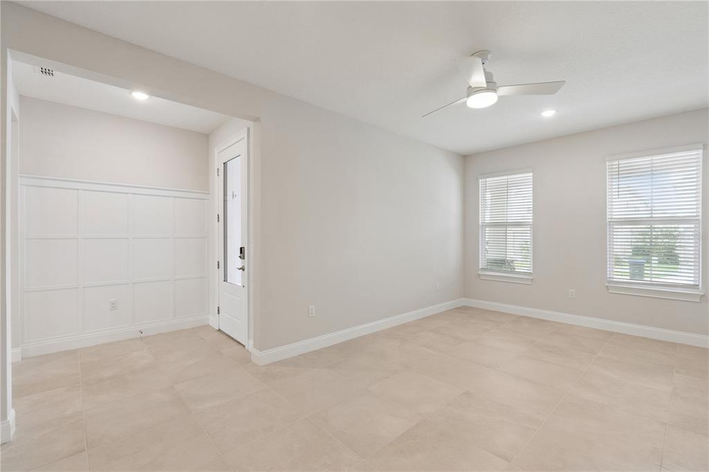 An empty room with light-colored tile flooring, white wainscoting, a ceiling fan, and two windows — 13129 FARO COURT, WINTER GARDEN, FL