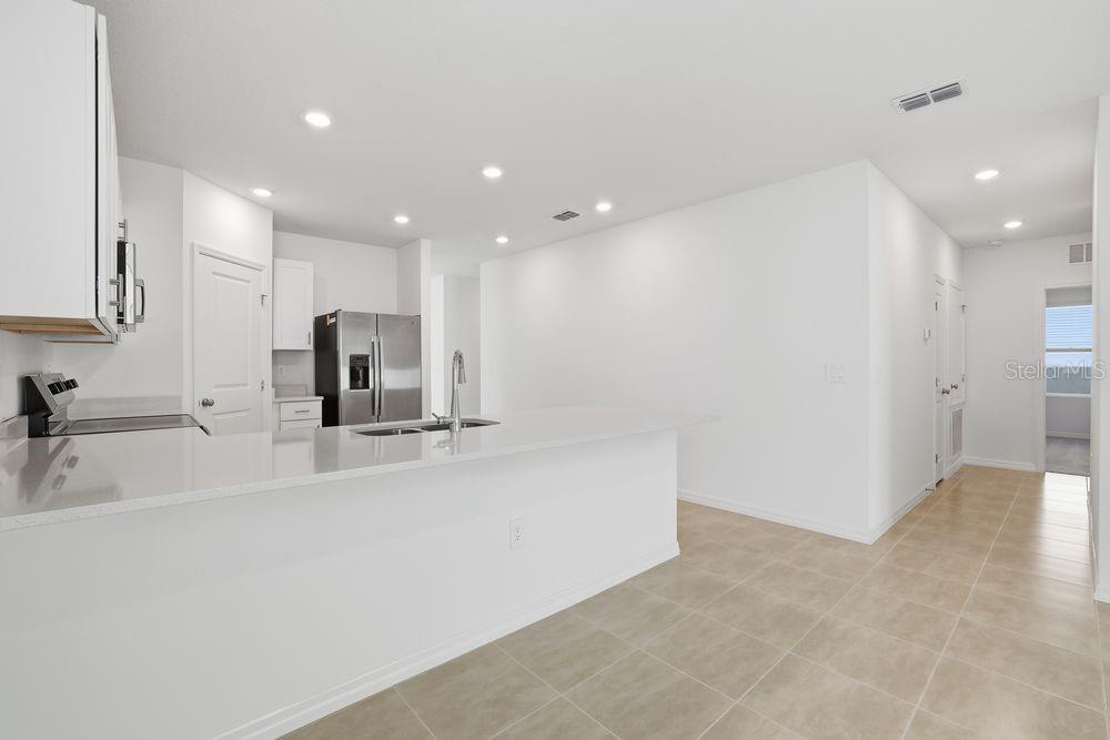 A modern kitchen features white cabinets, stainless steel appliances, and a spacious breakfast bar island — 13502 TROPICAL BREEZE WAY, HUDSON, FL