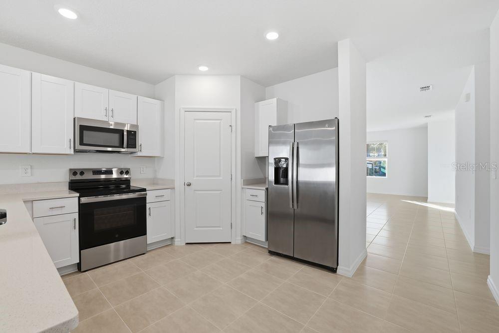 A kitchen with white cabinets, stainless steel appliances, and light tile flooring — 13502 TROPICAL BREEZE WAY, HUDSON, FL
