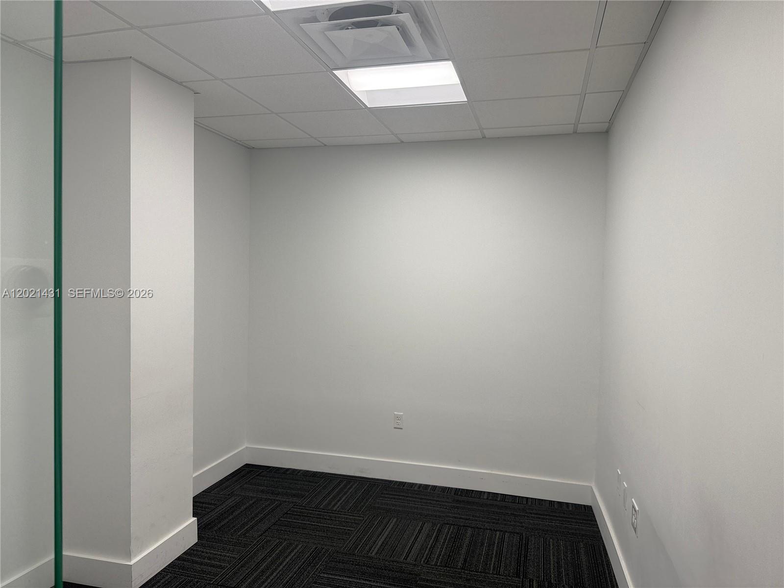 A small, empty office space features white walls, a drop ceiling, and dark carpet tiles — 290 NW 165th St # 2, Miami FL 33169, MIAMI, FL