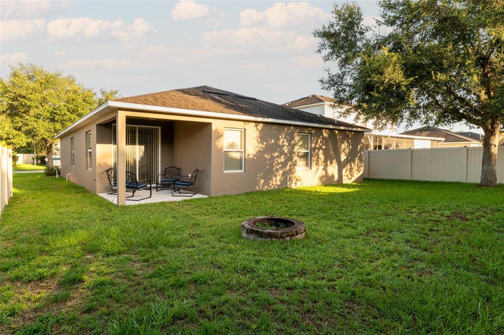 The backyard features a covered patio, a stone fire pit, and a vinyl privacy fence — 1569 TAMARIND ROAD, DAVENPORT, FL