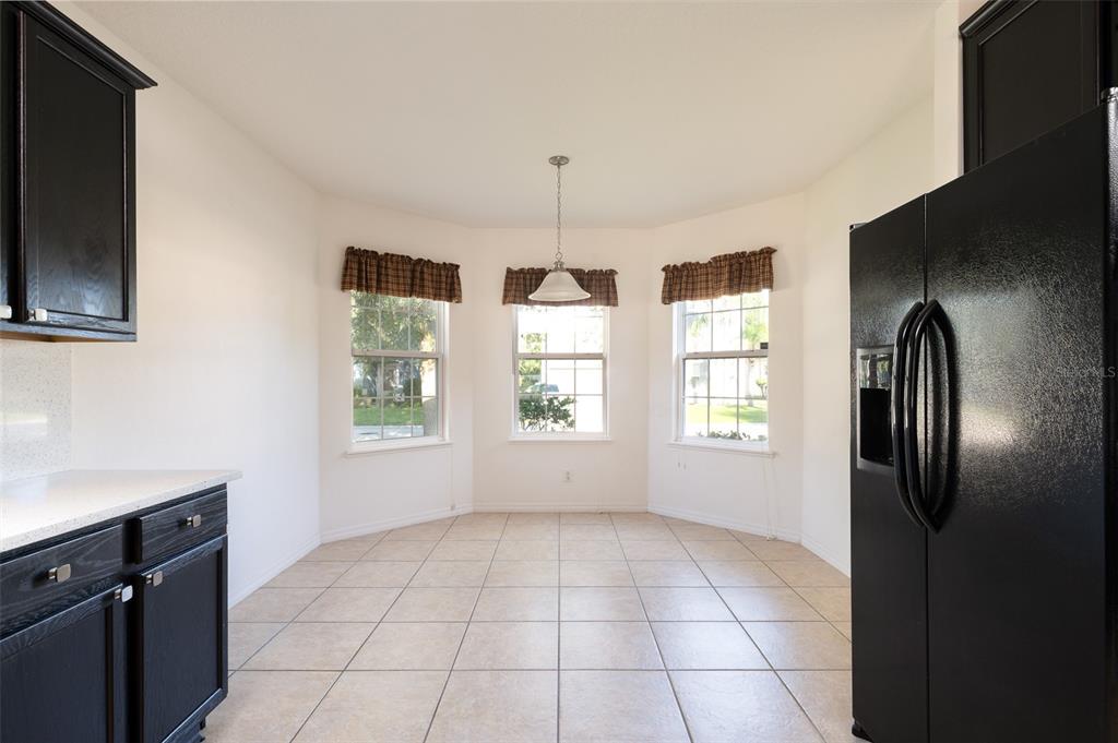 A kitchen breakfast nook with tile floors, black cabinets, a black refrigerator, and three windows — 1569 TAMARIND ROAD, DAVENPORT, FL