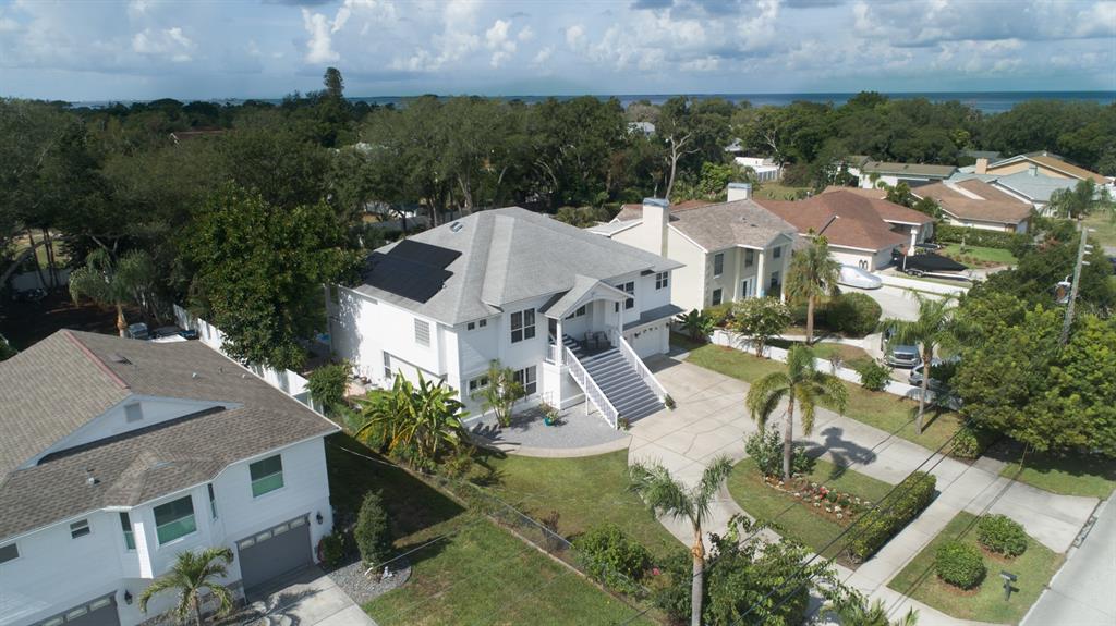 An elevated two-story house with a prominent staircase, solar panels, and a concrete driveway — 1605 GULF ROAD, TARPON SPRINGS, FL