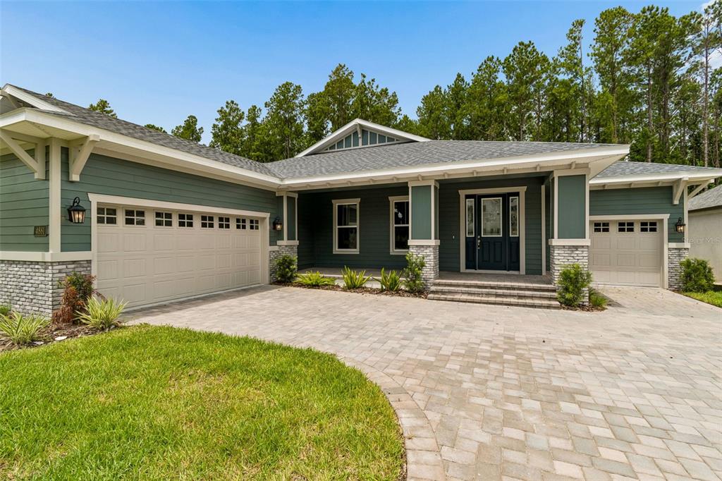 A single-story house with green siding, stone accents, and a paved driveway — 4881 MAJESTIC HILLS LOOP, BROOKSVILLE, FL