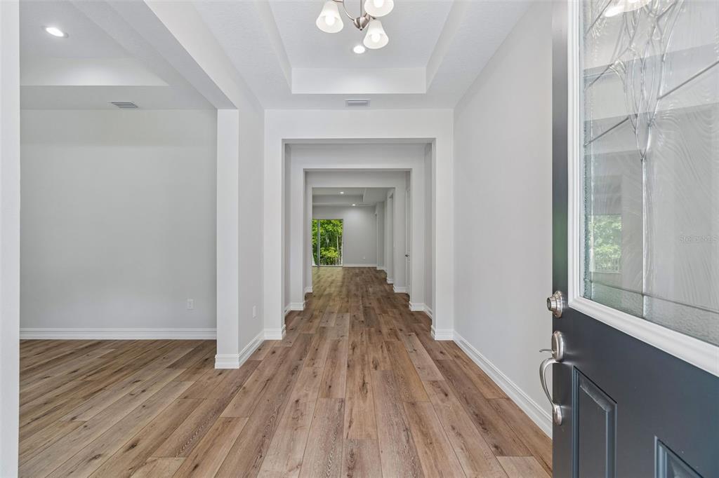 A view from an entryway looking down a long hallway with wood-look flooring — 4881 MAJESTIC HILLS LOOP, BROOKSVILLE, FL