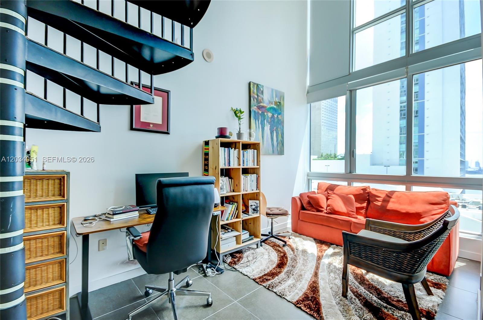 A home office features a spiral staircase, a desk, a bookshelf, and an orange sofa — 300 S Biscayne Bluv # 1022, Miami FL 33131, MIAMI, FL
