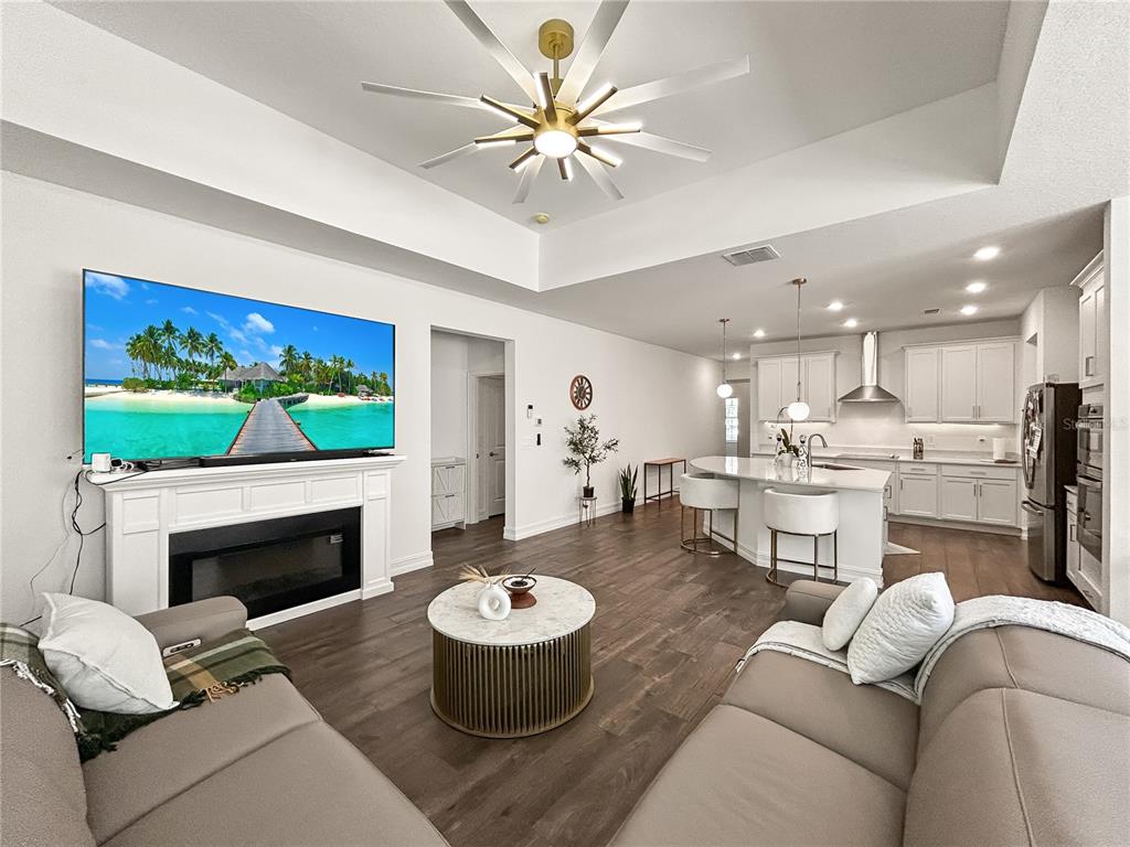 An open-concept living room and kitchen featuring a fireplace, large television, and central island — 18334 SERENE LAKE LOOP, LUTZ, FL