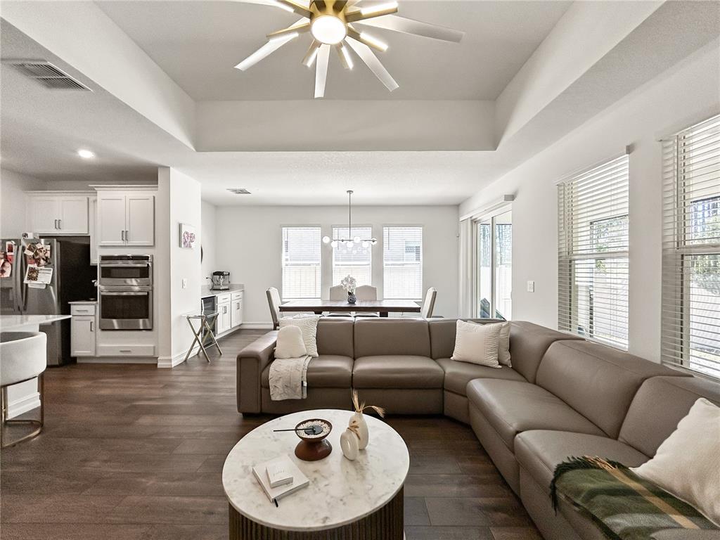 A spacious open-concept living room features a large sectional sofa, dining area, and kitchen — 18334 SERENE LAKE LOOP, LUTZ, FL