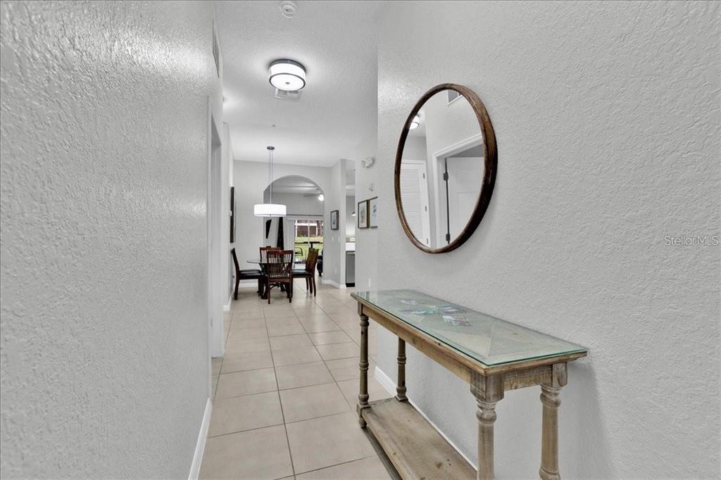 A hallway with tile flooring leads to a dining area featuring a glass-topped console table — 103 ROGUES RETREAT UNIT 22-103, DAVENPORT, FL
