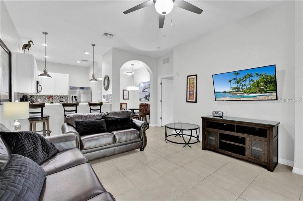 A living room with tile floors, a leather sofa, and a wall-mounted television — 103 ROGUES RETREAT UNIT 22-103, DAVENPORT, FL