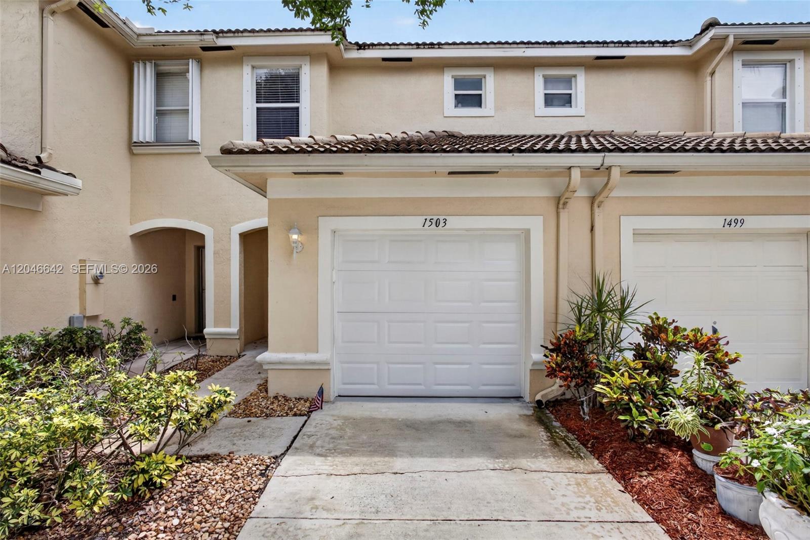 The exterior view shows a beige two-story townhouse with a single-car garage and landscaping — 1503 New Castle Ter, Wellington FL 33414, WELLINGTON, FL