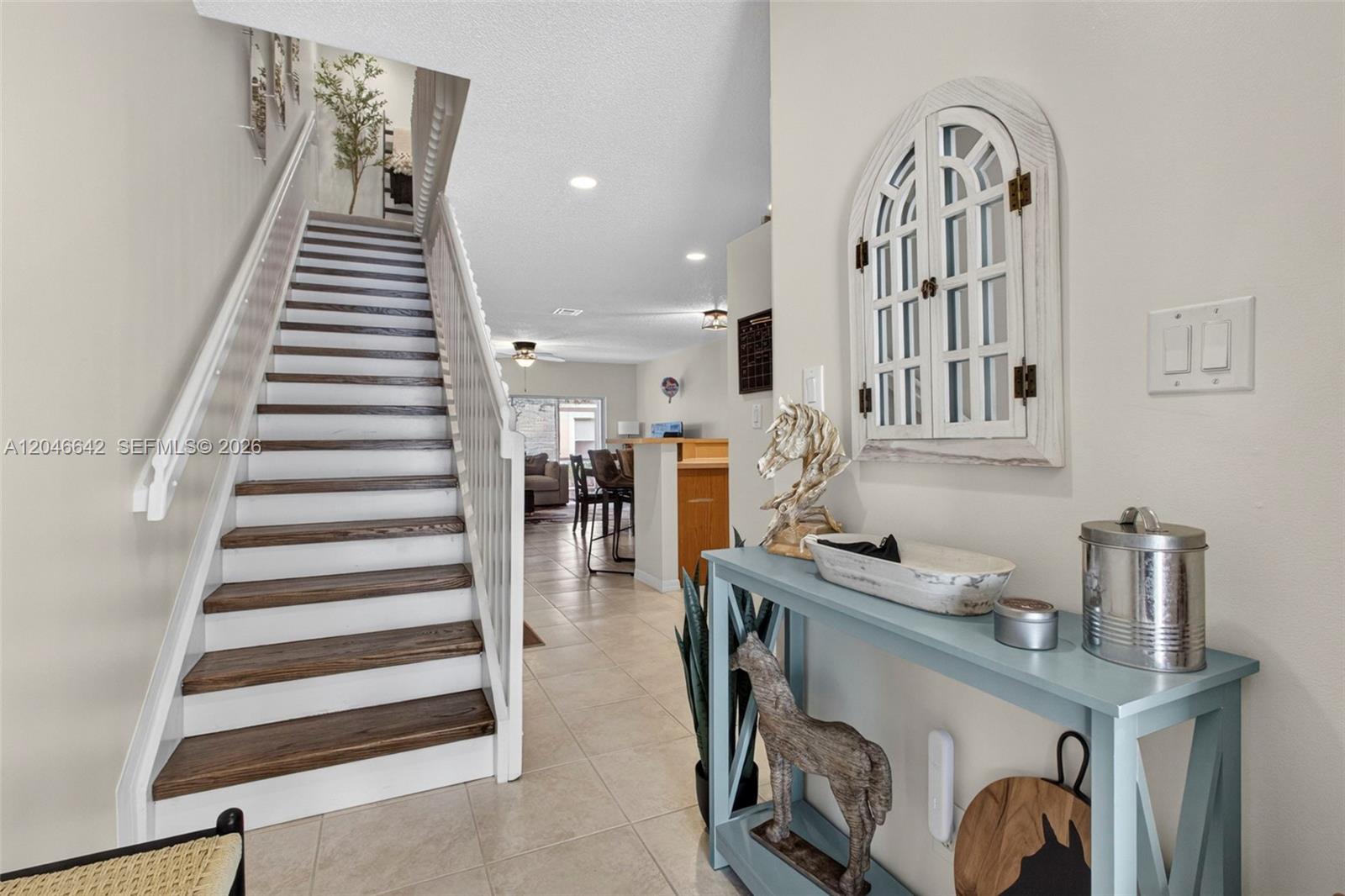 A staircase with wooden treads and white railings sits beside a blue console table — 1503 New Castle Ter, Wellington FL 33414, WELLINGTON, FL