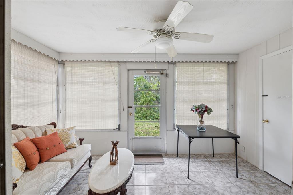 A sunroom features tile flooring, a ceiling fan, a sofa, a table, and a door — 4235 RICHMERE DRIVE UNIT 4235, NEW PORT RICHEY, FL