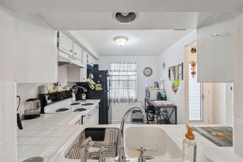 A kitchen features white cabinets, a black refrigerator, a white stove, and a double-basin sink — 4235 RICHMERE DRIVE UNIT 4235, NEW PORT RICHEY, FL