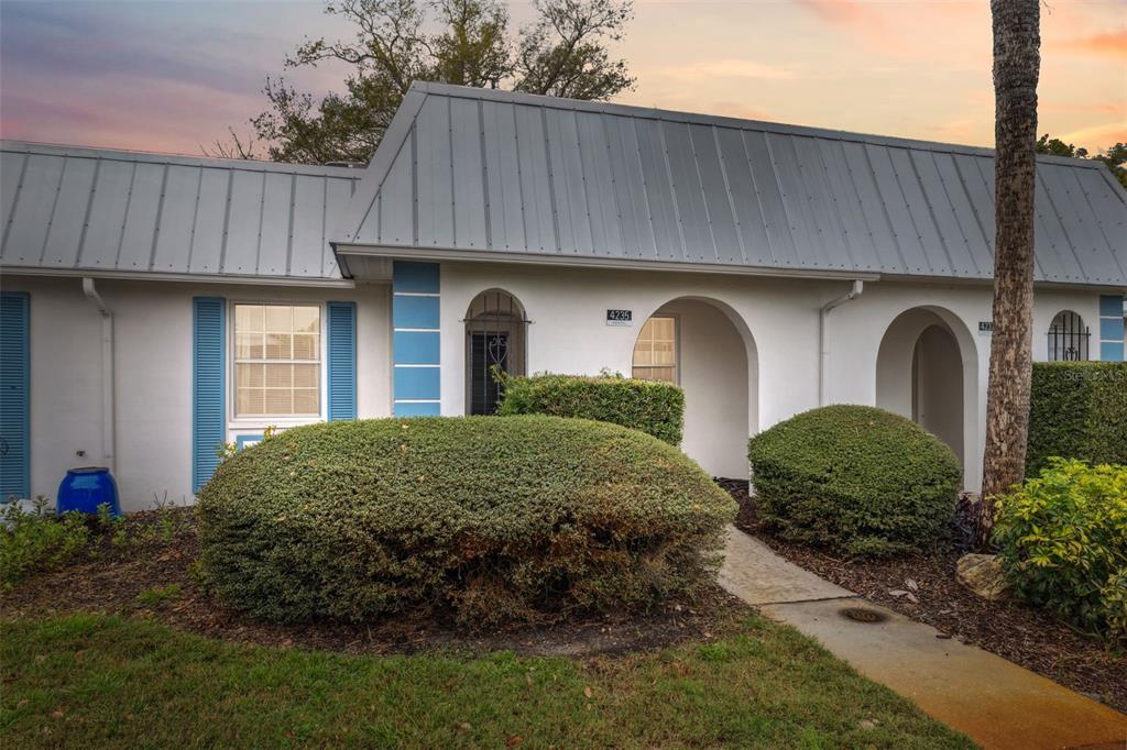 A single-story building with a metal roof, white stucco walls, and arched entryways — 4235 RICHMERE DRIVE UNIT 4235, NEW PORT RICHEY, FL