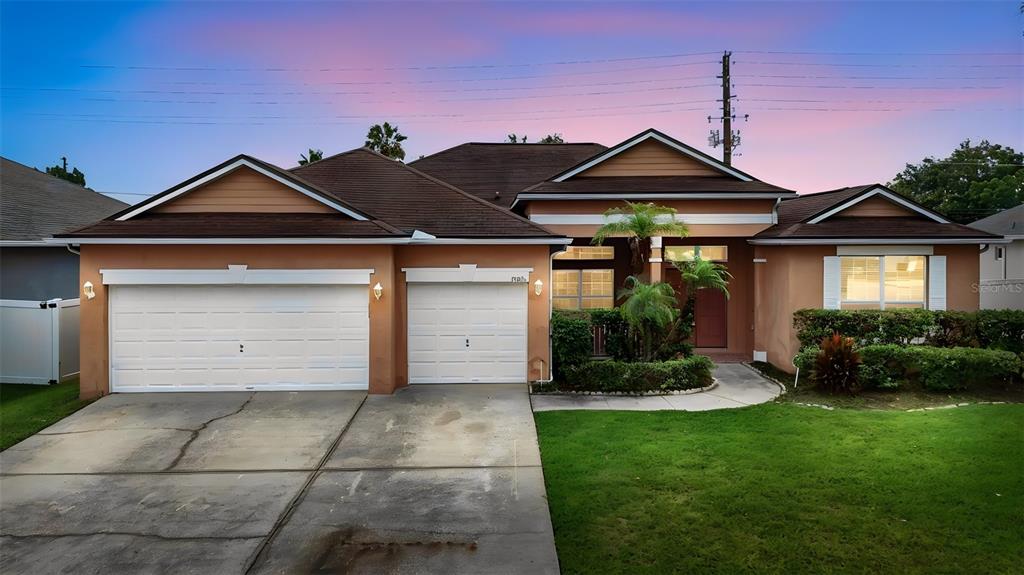 A single-story house with a two-car garage, tan stucco exterior, and a landscaped front yard — 13618 OLD DOCK ROAD, ORLANDO, FL