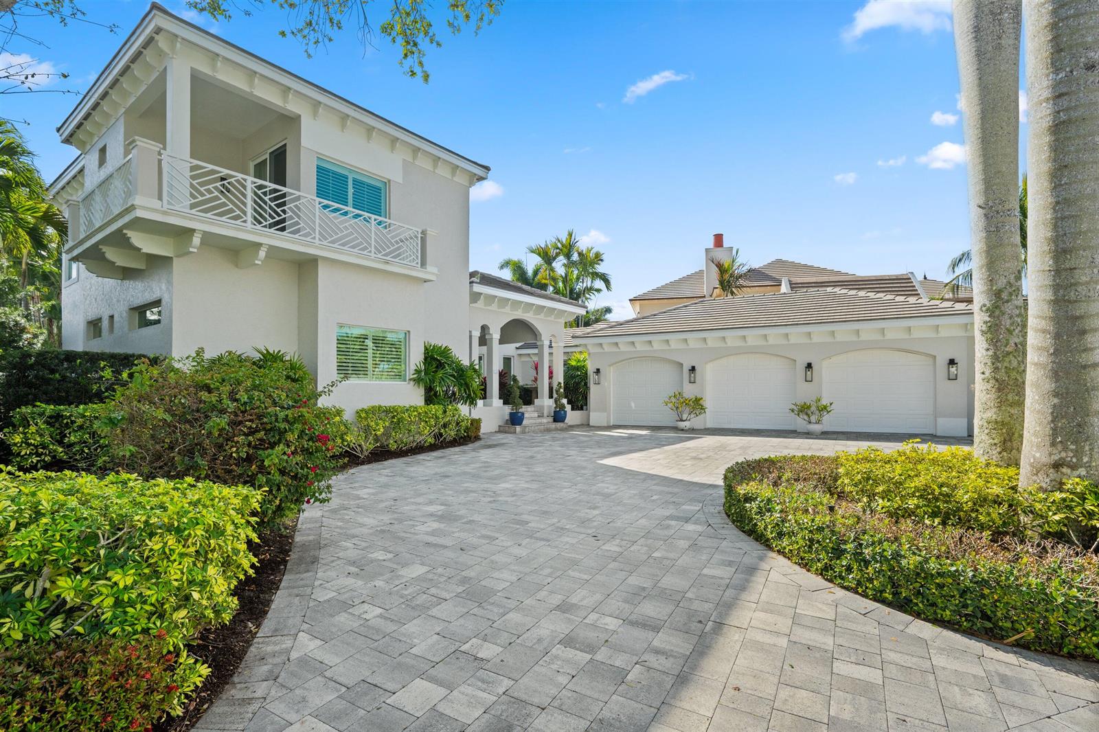 A two-story house with a paved driveway, three-car garage, and lush landscaping under a blue sky — 116 Terrapin Trail, Jupiter FL 33458, JUPITER, FL