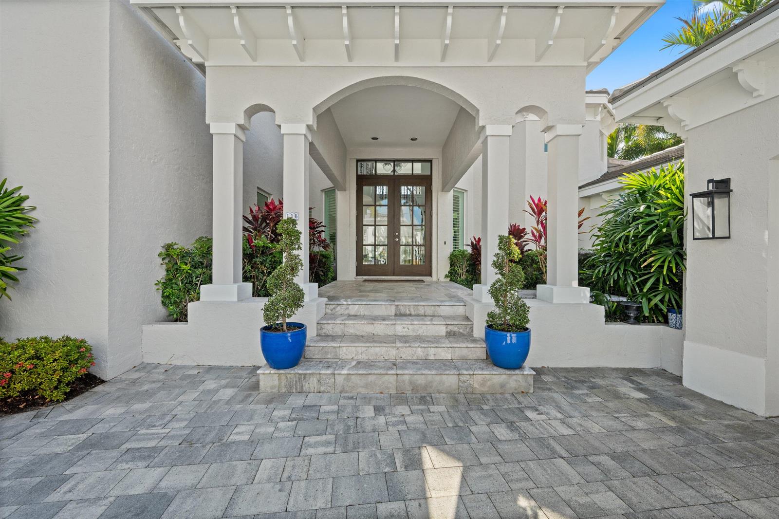 The exterior entrance features a covered porch with white columns, stone steps, and blue planters — 116 Terrapin Trail, Jupiter FL 33458, JUPITER, FL
