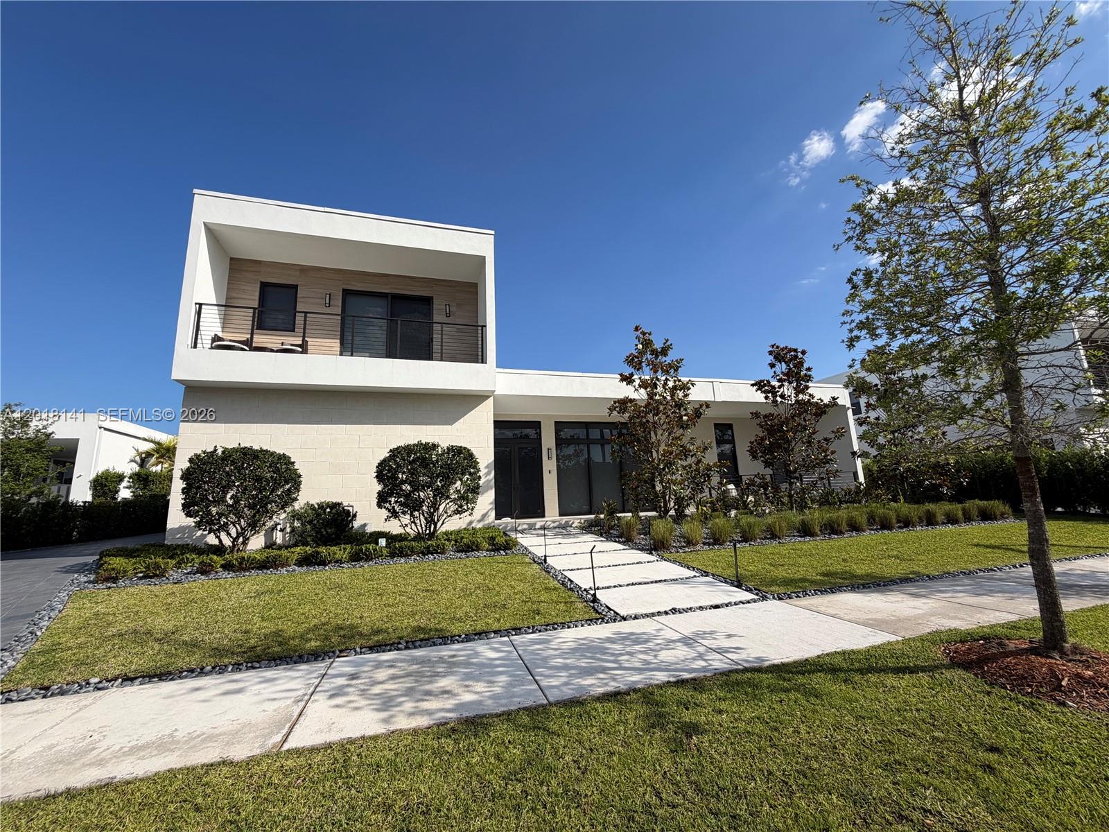 A modern two-story house features a white exterior, a balcony, and a paved walkway — 16786 Natures Way, Weston FL 33326, WESTON, FL