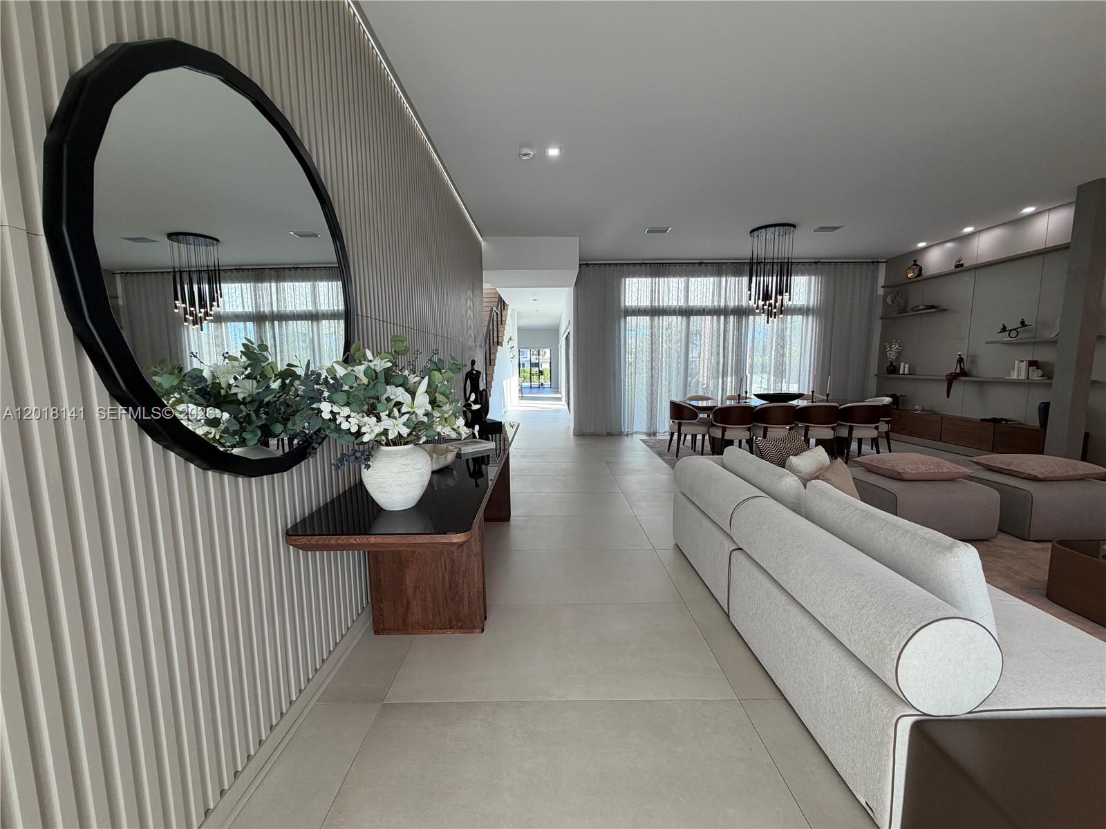 A modern living and dining area features a slatted wall, a round mirror, and tile flooring — 16786 Natures Way, Weston FL 33326, WESTON, FL