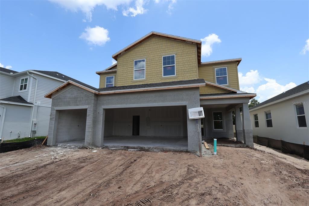A two-story suburban house features a three-car garage, stone accents, and a paved driveway — 6741 YELLOW WARBLER BEND, ST CLOUD, FL