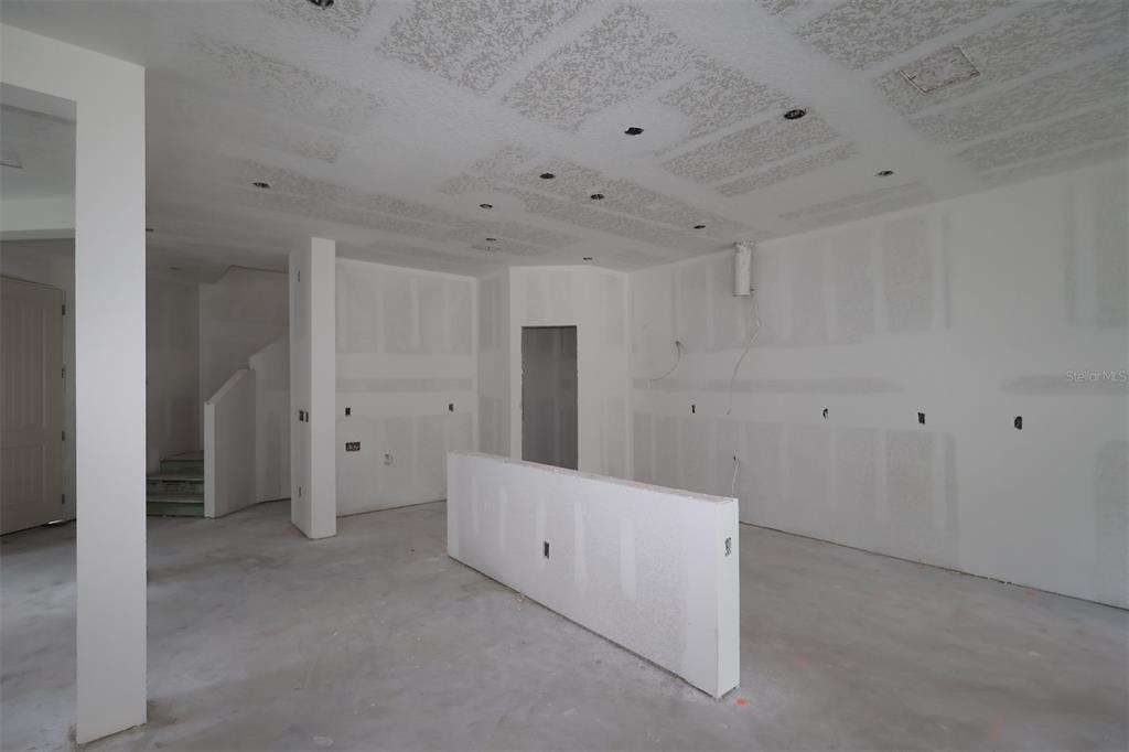 A kitchen under construction features white cabinets, a central island, and protective paper on floors — 6741 YELLOW WARBLER BEND, ST CLOUD, FL