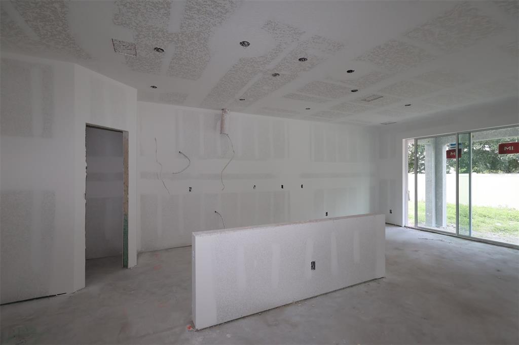 An unfinished kitchen features white cabinets, a central island, and protective paper covering the floor — 6741 YELLOW WARBLER BEND, ST CLOUD, FL