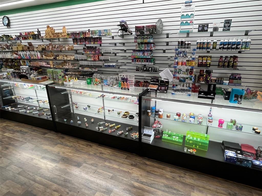 A retail store interior features glass display cases filled with smoking accessories and wall shelving — 5915 MEMORIAL HIGHWAY, TAMPA, FL
