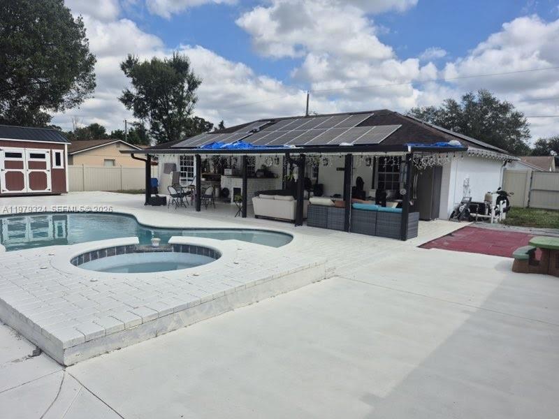 A backyard features a swimming pool, a hot tub, and a covered patio with solar panels — 8016 APACHE LN, Lakeland FL 33810, LAKELAND, FL