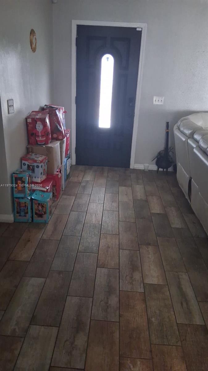 A living room entryway features wood-look tile flooring, a dark front door, and stacked boxes — 8016 APACHE LN, Lakeland FL 33810, LAKELAND, FL