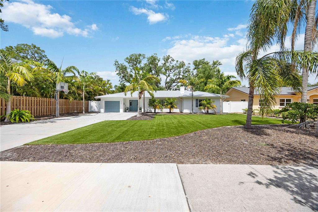 A single-story white house with a metal roof, palm trees, and a concrete driveway — 1865 ORCHID STREET, SARASOTA, FL