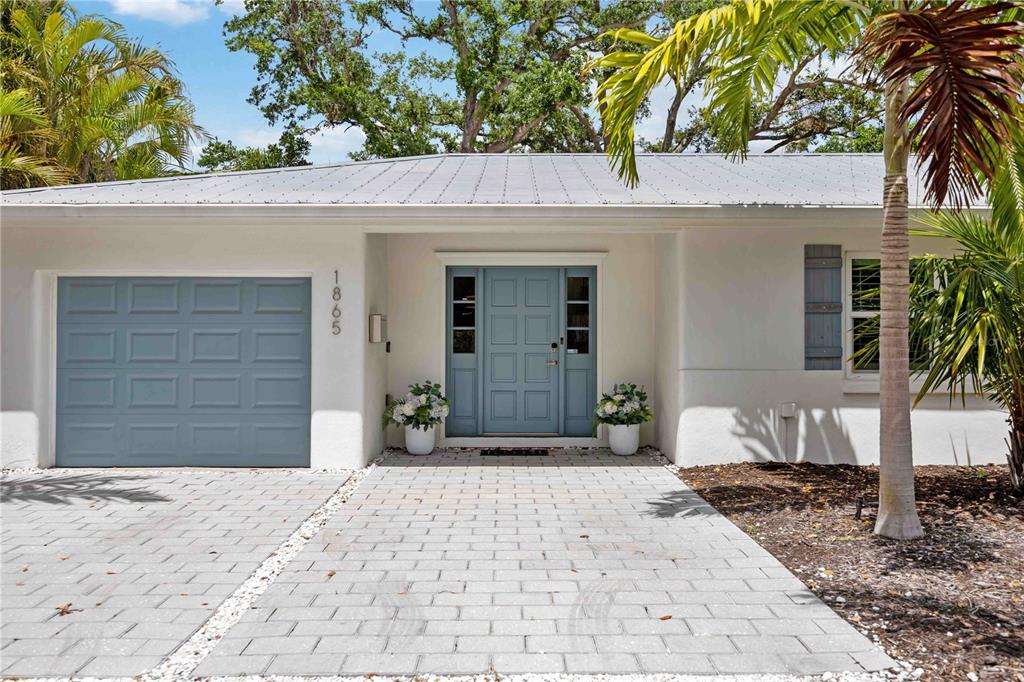 A single-story house with a blue front door, garage door, and a paved walkway — 1865 ORCHID STREET, SARASOTA, FL