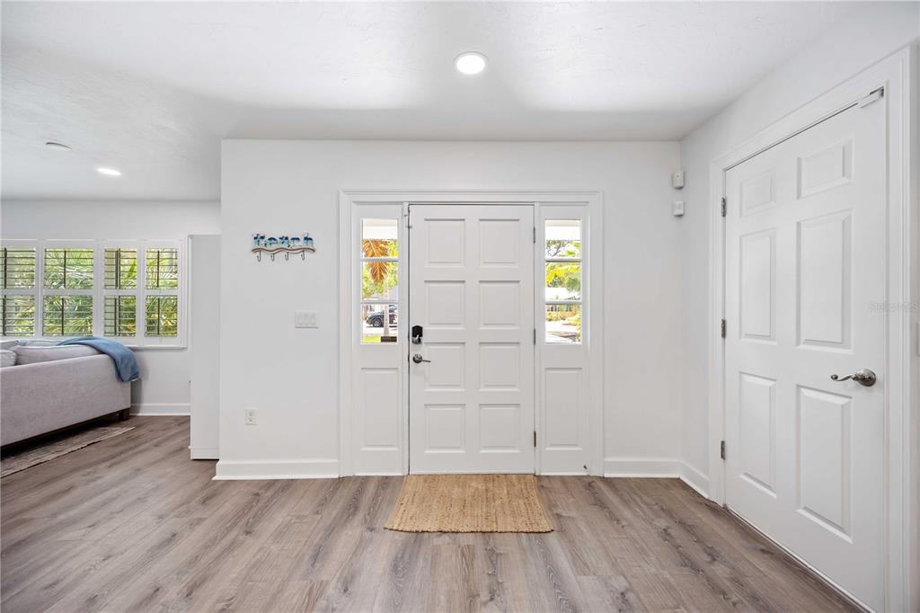 An entryway features white walls, wood-look flooring, a front door with sidelights, and a closet — 1865 ORCHID STREET, SARASOTA, FL