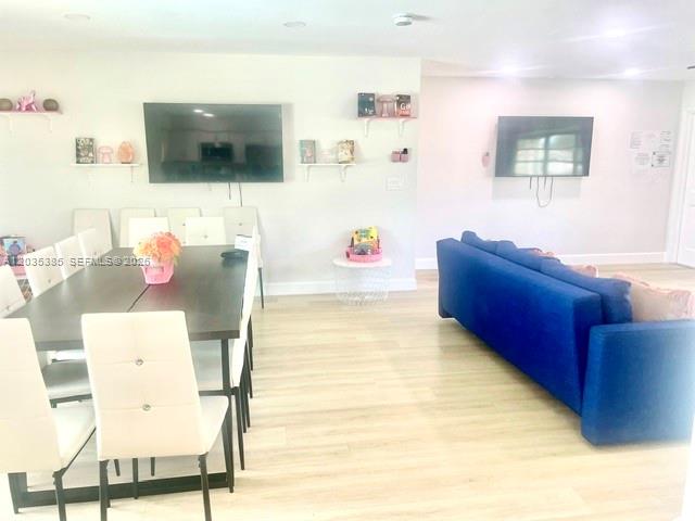 A dining area with a dark table and white chairs sits beside a blue sofa — HOLLYWOOD, FL