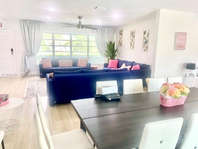 A living room features a blue sectional sofa, a dining table, and large windows — HOLLYWOOD, FL