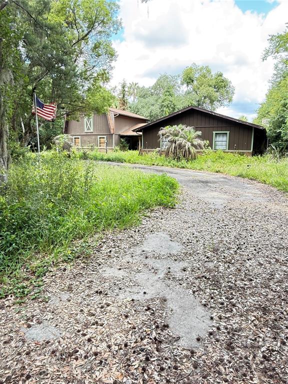 A brown house with a gambrel roof stands at the end of a gravel driveway — 2260 HONTOON ROAD, DELAND, FL