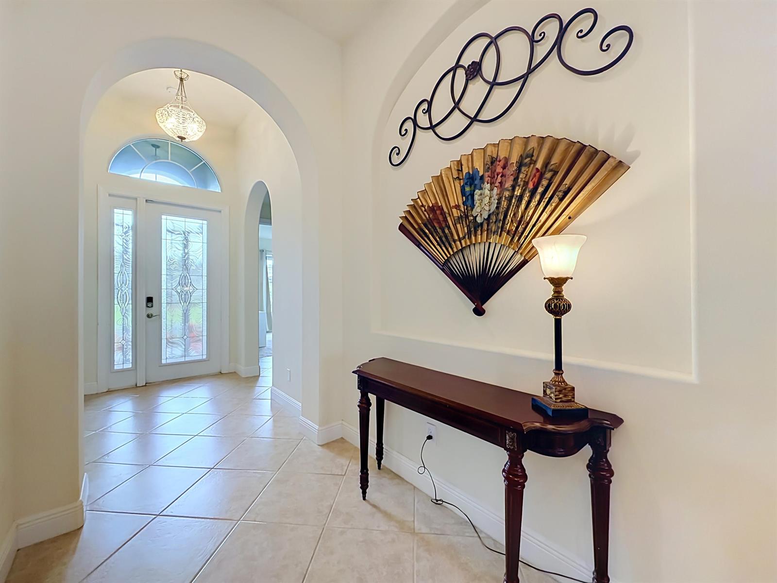 An entryway features a tiled floor, arched doorways, a console table, and wall decor — 728 Fortunella Circle SW, Vero Beach FL 32968, VERO BEACH, FL