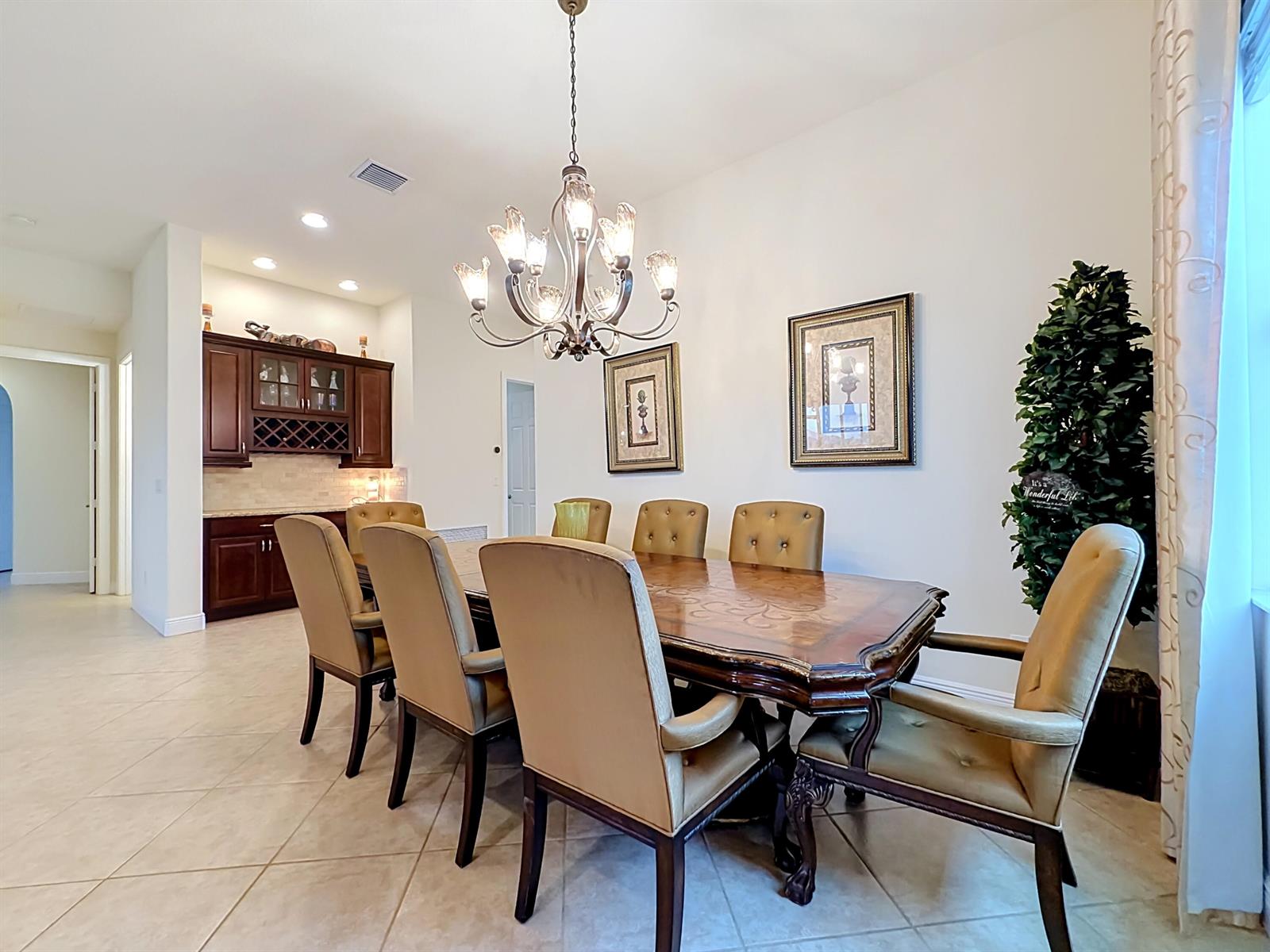 A dining room features a wooden table with upholstered chairs, a chandelier, and built-in cabinetry — 728 Fortunella Circle SW, Vero Beach FL 32968, VERO BEACH, FL