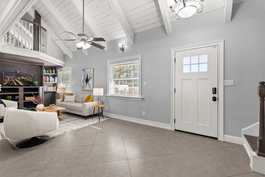 A living room features vaulted ceilings, tile flooring, a white front door, and built-in shelving — 8255 LAKE UNDERHILL ROAD, ORLANDO, FL