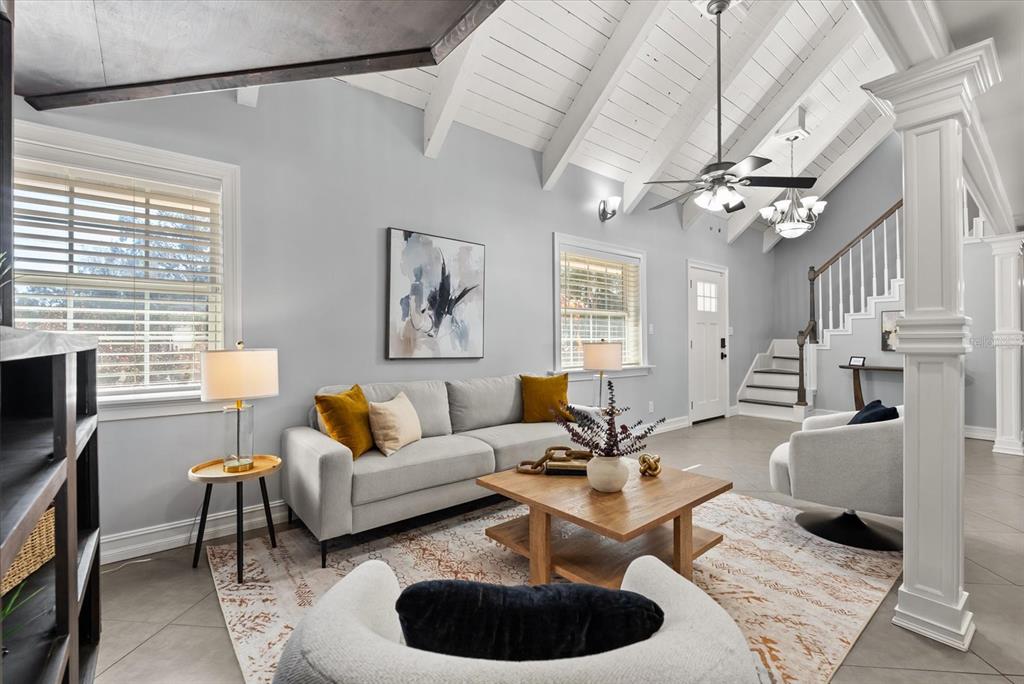 A living room features a vaulted ceiling, gray walls, a staircase, and modern furniture — 8255 LAKE UNDERHILL ROAD, ORLANDO, FL