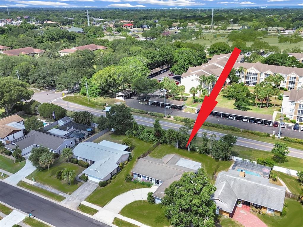 An aerial view shows a residential house with a pool and a red arrow pointing toward it — 878 RUSTIC OAKS DRIVE, PALM HARBOR, FL